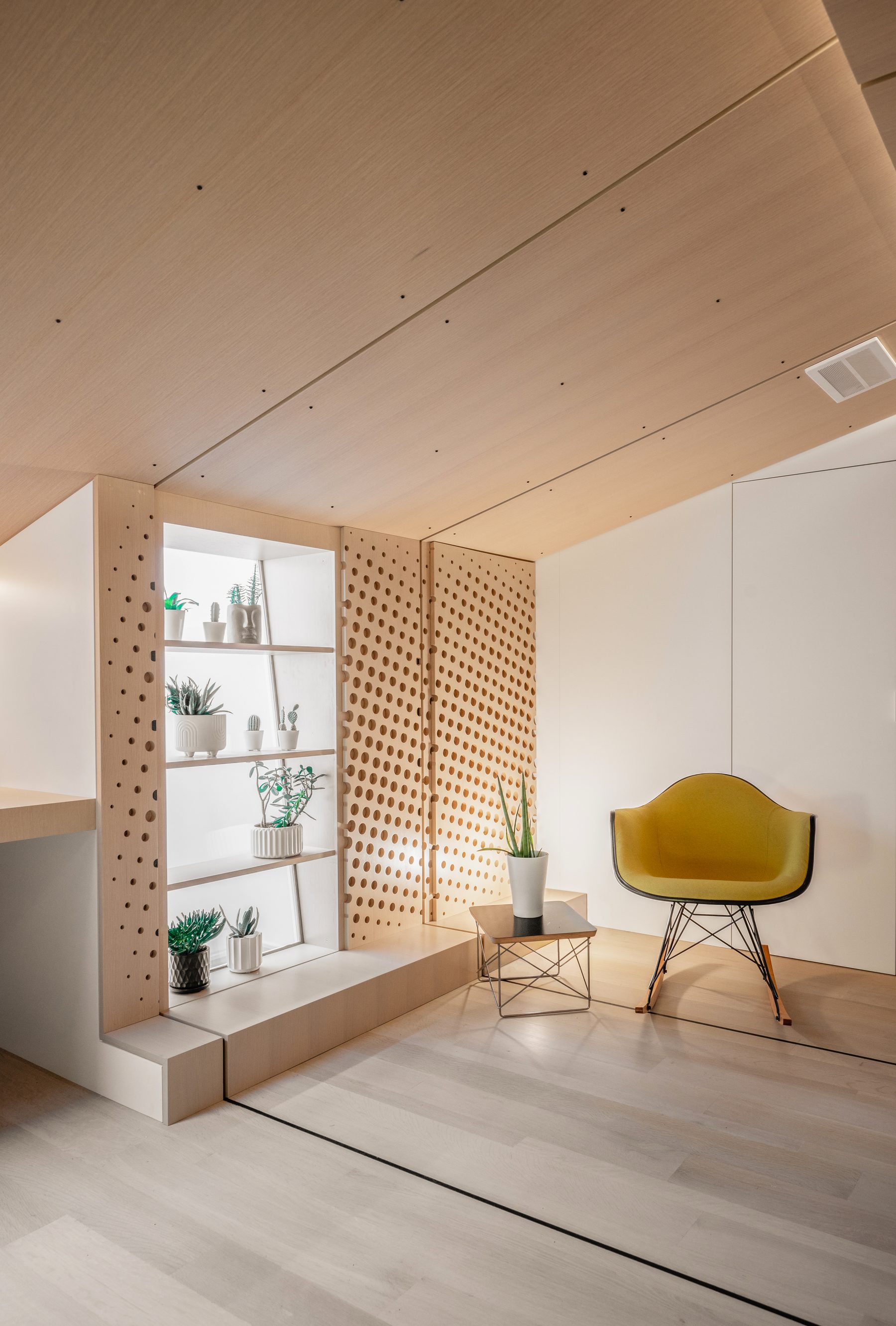 Perforated white oak shelf niche borrowing light from an existing skylight