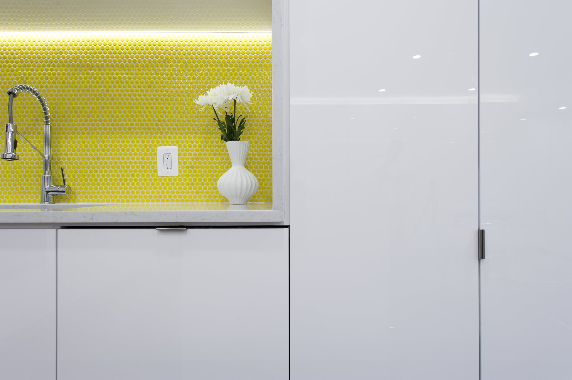 Detail of yellow penny-round tile niche and gloss white cabinetry